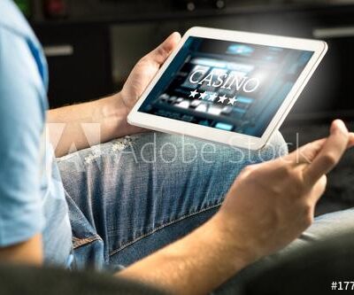 Excited man playing in an online casino with tablet fingers crossed wishing and hoping to win. Slot machine app. Person holding smart mobile device in hand at home.